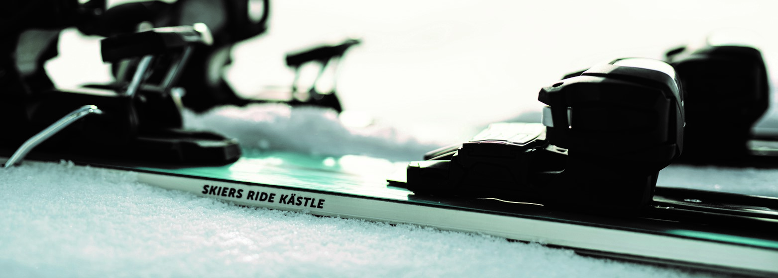 Eine Nahaufnahme einer Skibindung auf einer weißen Schneedecke. Auf der Seite des Skis ist der Schriftzug „Skiers Ride Kästle“ zu lesen, während die Bindung den Fokus des Bildes einnimmt.